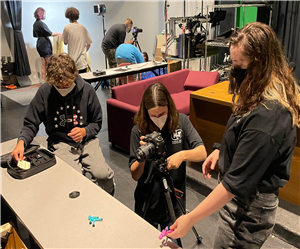 3 students set up a toy and camera for a studio photo shoot